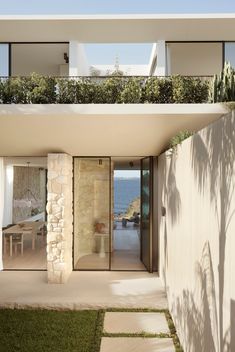 the house is made out of stone and has glass doors that lead to an outdoor deck