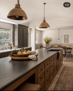 a large kitchen with lots of counter space and hanging lights over the top of it