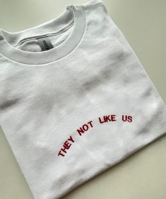 They Not Like Us, Embroidered T-shirt, Monogram, Funny T-shirt, Unisex, SHIPPING INFO: FREE UK DELIVERY are sent as 1st Class (1-2 Working days) UK EXPRESS (Next day delivery) this is an extra cost at checkout Europe sent as International Tracked (Expected 3-5 working days) Worldwide sent as International Tracked (Expected 5-7 working days) EMBROIDERY THREAD: POLYESTER T-SHIRT: 100% COTTON (WHITE 170 GSM) (OTHER COLS 180 GSM) SWEATSHIRT: 80% COTTON, 20% POLYESTER (WHITE + HEATHER GREY 260 GSM) ( Red Embroidered Logo T-shirt For Streetwear, Graphic Tee With Embroidered Logo And Crew Neck, Graphic Tee With Embroidered Logo, Cotton Crew Neck T-shirt With Text Print, Red Crew Neck T-shirt With Embroidered Logo, White Crew Neck T-shirt With Embroidered Logo, Red Crew Neck Top With Embroidered Logo, Crew Neck Graphic Tee With Embroidered Logo, Embroidered Logo Graphic Tee With Crew Neck