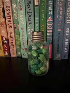 a glass jar filled with green candy sitting on top of a table next to books