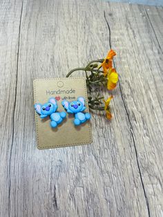 two little blue elephants sitting on top of a wooden table next to some yellow flowers