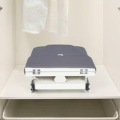 an open suitcase sitting on top of a shelf in a closet with clothes hanging from hooks