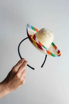 a hand holding a straw hat on top of a headband