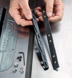 a man is working on some metal parts with his hands and tools in front of him