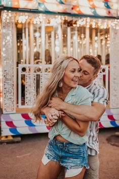 a man and woman hugging in front of a merry go round