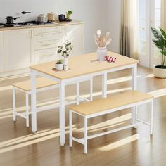 a kitchen table with two benches next to it and a potted plant on the counter