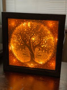 an illuminated tree in a wooden frame on a table