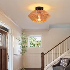 a living room filled with furniture next to a stair case under a light above a window