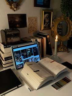 an open book sitting on top of a laptop computer next to a pile of books