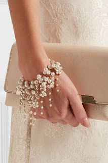 a woman's hand holding a purse with pearls on it