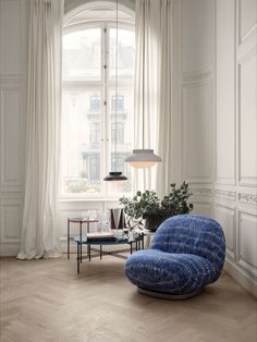 a blue chair sitting in front of a window next to a table with a potted plant