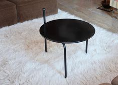 a black coffee table sitting on top of a white fluffy rug next to a couch