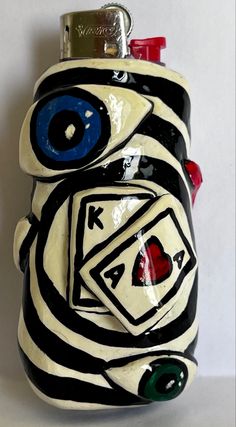 a black and white ceramic object with blue eyes on it's face, holding a lighter