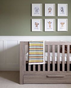 a baby crib with four pictures on the wall