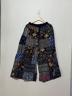 Welcome to my shop! This is a handmade Unisex Patchwork Palazzo Pant made from soft, comfortable cotton material. The length of this pant is approximately 38-40 inches and the waist measures 26 inches, stretching up to 45 inches due to the elastic material and drawstring closure. It features a regular waist style and comes in item number MG 007. The patchwork on this pant is done with different patterns, giving it a unique and bohemian look. The cute tassels add a fun touch and the elastic waist and ankle make it perfect for relaxing at home, working out, or doing yoga. This pant is made with soft rayon fabric, making it a comfortable and stylish choice. Please note that due to lighting and monitor settings, the color of the product may slightly vary. As this is a hand patchwork, there may Cotton Patchwork Wide-leg Pants, Summer Patchwork Wide-leg Bottoms, Summer Patchwork Full Length Bottoms, Summer Full-length Patchwork Bottoms, Bohemian Cotton Bottoms With Patchwork, Bohemian Wide Leg Bottoms With Patchwork, Festival Patchwork Wide Leg Bottoms, Wide Leg Patchwork Bottoms For Festival, Red Patchwork Bottoms For Spring