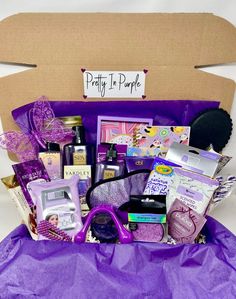 a purple gift box filled with lots of beauty and personal care items sitting on top of a purple bag