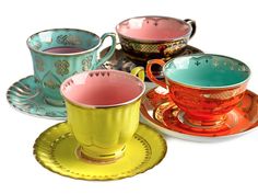 four different colored cups and saucers sitting on top of each other