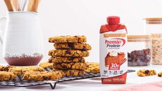 cookies and milk on a cooling rack next to a vase with straws in it