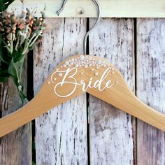 a wooden wedding hanger with the word bride written on it next to some flowers