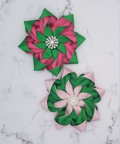 two flower brooches sitting on top of a marble counter