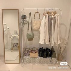 a white closet filled with lots of clothes and handbags next to a large mirror