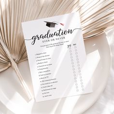 a graduation checklist on a plate next to an open book with a fan in the background