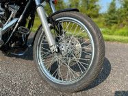 a motorcycle parked on the side of a road next to grass and trees in the background