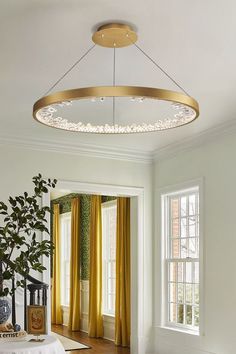 a living room filled with furniture and a round light fixture hanging from the ceiling over a table