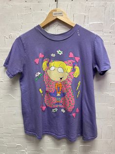 Vintage Rugrats Angelica Pickles T-Shirt | Vintage T-Shirt | Rugrats Tee | Angelica Pickles | Nickelodeon Tee | Size Youth 14 | SKU NPC-1382 Used - Bleach stains along collar (please refer to photos).  Size 14 (youth) on tag, fits like a women's XS/S. Please refer to photos for measurements Chest 18 1/2" Length 21 1/2" Cotton    We only ship to the US and Canada. All our items of vintage condition. Most of the items have minor defects such as holes, stains, cracking on the print, and pilling. Pl Rugrats In Paris, Angelica Pickles, Nickelodeon, Vintage Tshirts, Pickles, Favorite Outfit, Gender Neutral, Bleach, Art Collection