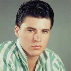 a man with black hair wearing a green and white striped shirt looking at the camera