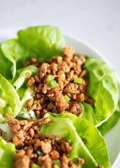 lettuce leaves with ground meat and onions in them on a white plate, ready to be eaten