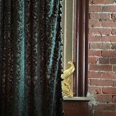 the curtain is open in front of a brick wall with a mirror on top of it