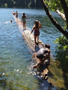 several people in bathing suits standing on the edge of a body of water with trees