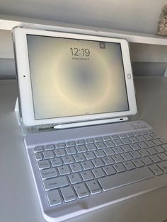 an ipad keyboard sitting on top of a white desk next to a mouse and tablet