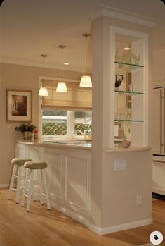 a kitchen with two stools next to an island and bar in the middle of it