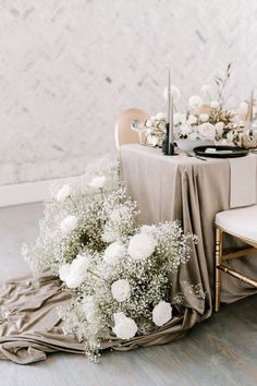 a table set up with white flowers and silverware