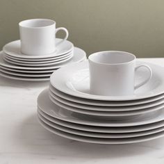 a stack of white cups and saucers sitting on top of a table next to each other