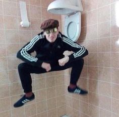 a man is jumping in the air near a urinal with his hands on his hips