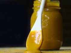 a spoon full of peanut butter sitting on top of a wooden table next to a jar