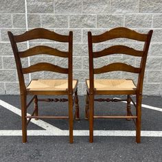 two wooden chairs sitting side by side in a parking lot