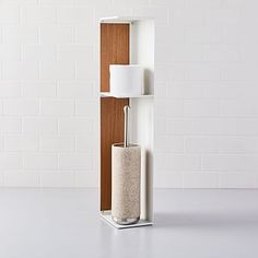 a tall white shelf with a lamp next to it and a toilet paper roll in the corner