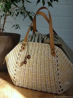 a wicker bag sitting on top of a wooden table next to a potted plant