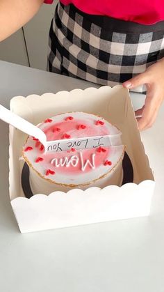 a person cutting into a cake in a box with the word wow written on it