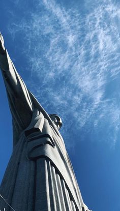 the statue is tall and has a bird perched on it's head in front of a blue sky with wispy clouds