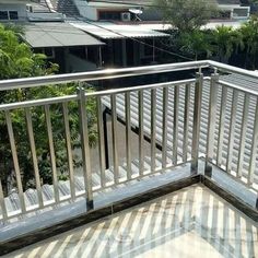 an empty balcony with white railings and trees in the backgroung area