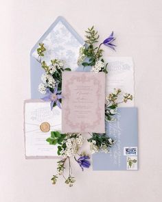 the wedding stationery is laid out on top of each other with purple and white flowers