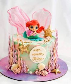 a birthday cake with a little mermaid sitting on top of it