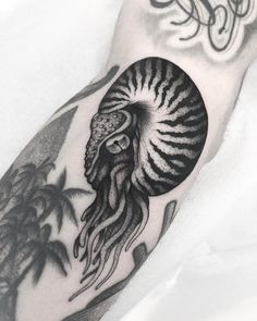 a man's arm with an octopus and palm trees tattoo on the left forearm