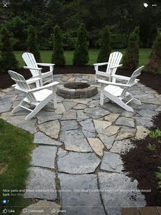 two white adironda chairs sitting on top of a stone patio next to a fire pit