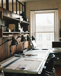 an office with desk, bookshelf and two lamps on the windowsills